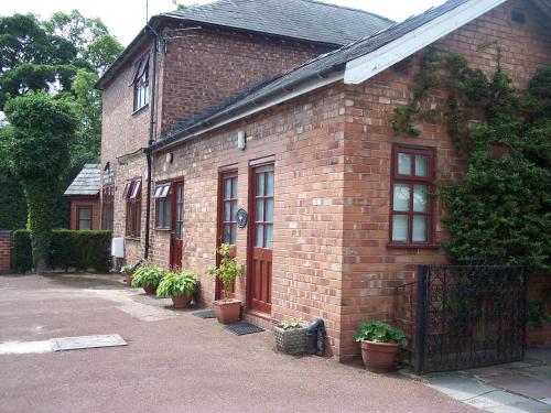 a brick house with potted plants in front of it at Butterfly Guest House in Cheadle