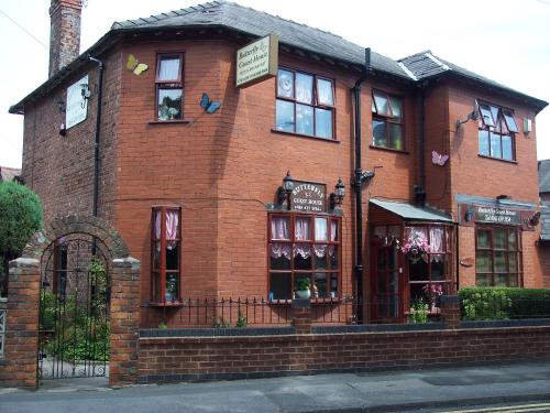 a red brick building with a sign on it at Butterfly Guest House in Cheadle