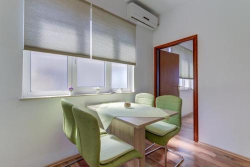 a dining room with a table and green chairs at Apartment Žuna in Senj