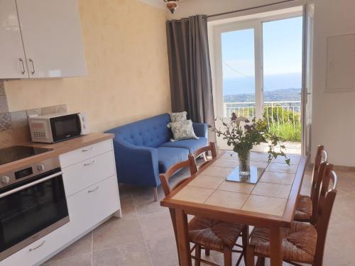 Il comprend une cuisine et un salon avec une table et un canapé bleu. dans l'établissement Appartement A Caserella entièrement rénové avec terrasse et vue panoramique sur mer, à Valle-di-Campoloro