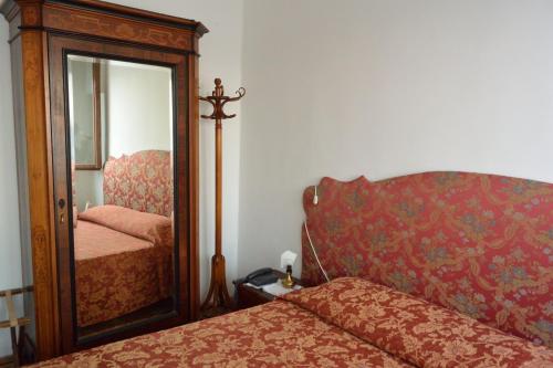 a bedroom with a mirror next to a bed at Pensione Seguso in Venice