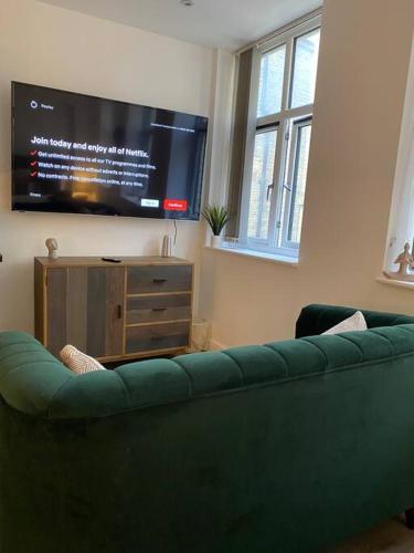 a living room with a green couch and a flat screen tv at Brand New Property - Bradford City Centre in Bradford
