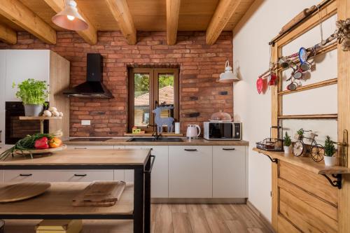 a kitchen with white cabinets and a brick wall at Mountain house Beauty of Laz in Ravna Gora