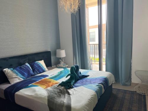 a green dinosaur sitting on a bed in a bedroom at Relaxing villa with access to pool and beach in Ras al Khaimah