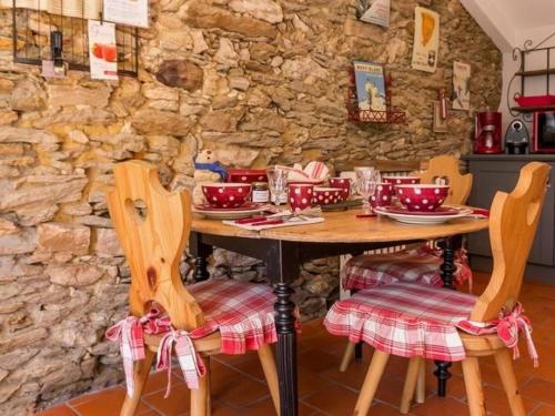 une table en bois avec des chaises et un mur en pierre dans l'établissement Gîte Accessible avec Jardin Fleuri près de Pornic, Éco-rénové et Équipé (Vélos, WiFi, Cheminée) - FR-1-306-957, à La Sicaudais