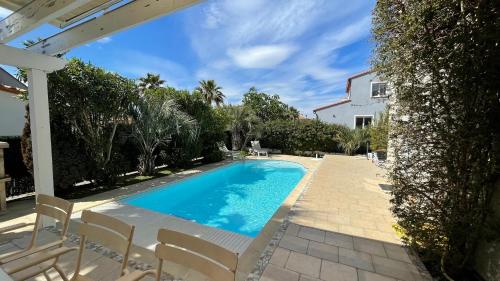 une piscine avec des chaises et une maison dans l'établissement La maison de Virginie 6 a 12 personnes -300 m de la plage- vélos a disposition, à Saint Cyprien Plage
