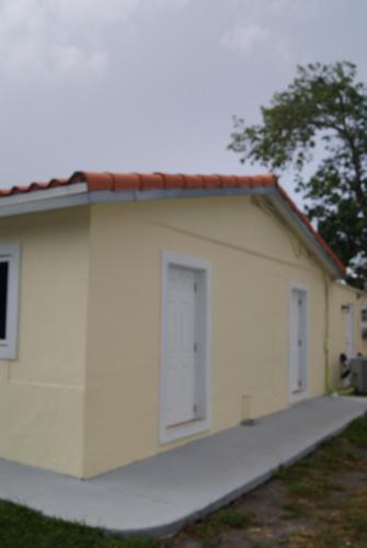 a white building with three doors on it at Private Studio two miles from Hard Rock Stadium in Miami Gardens