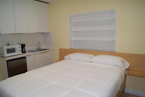 1 dormitorio con cama blanca y microondas en Private Studio two miles from Hard Rock Stadium en Miami Gardens