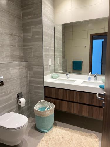 a bathroom with a toilet and a sink and a mirror at Relaxing villa with access to pool and beach in Ras al Khaimah