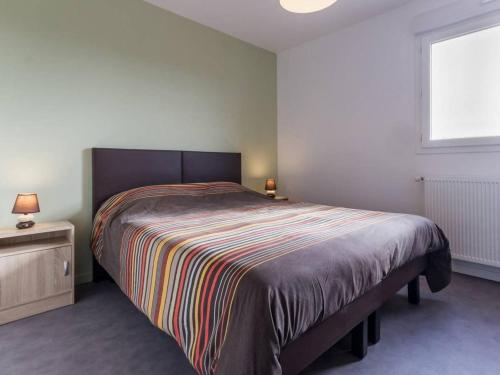 - une chambre avec un grand lit et une couverture rayée dans l'établissement Gîte calme proche mer à Pornic, jardin clos, accessible PMR, visite ferme, wifi, équipement bébé - FR-1-306-1067, à Pornic
