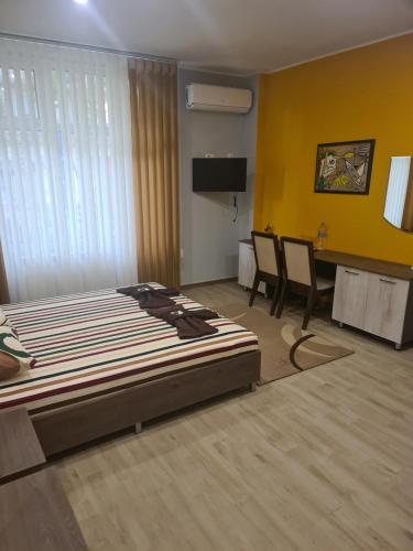 Dormitorio con cama, escritorio y TV en Семеен хотел Аристо en Dryanovo