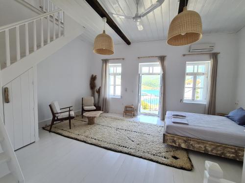 a bedroom with a bed and a chair and windows at Townhouse Christos in Panormos Skopelos