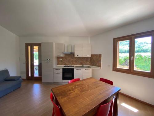 cocina con mesa de madera y sillas rojas en Villino La Funtana, en San Teodoro