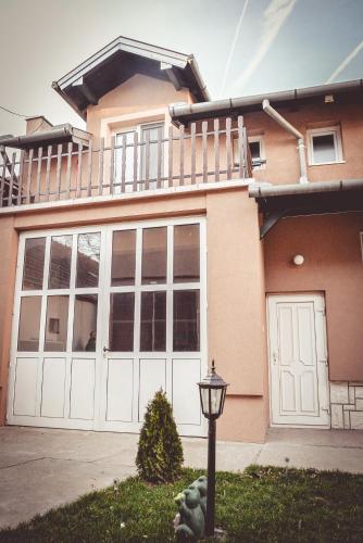 a house with white garage doors and a balcony at Royal TSV Rooms in Sombor