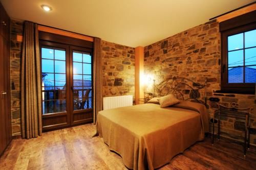 a bedroom with a bed and a stone wall at Hotel Rural La Casa del Peregrino in El Acebo de San Miguel