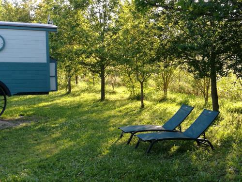 a chair sitting in the grass next to a rv at Gîtes Les Perouilles - La Roulotte Climatisée avec Jacuzzi de Josépha in Puymiclan