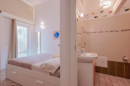 biała sypialnia z łóżkiem i umywalką w obiekcie Approdo Rooms - Eja Sardinia w Cagliari