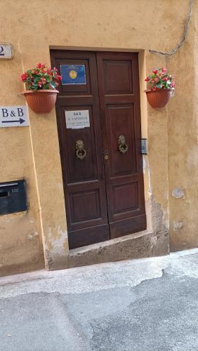 a brown door on a building with two plants at il CAPITELLO in Rieti