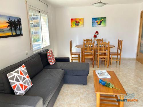 een woonkamer met een bank en een tafel bij APARTBEACH NOVA PINEDA con PARKING Y CLIMA in La Pineda