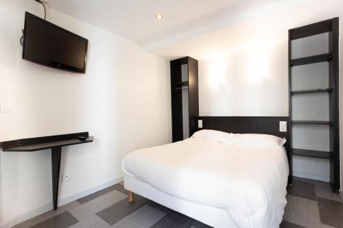 a bedroom with a bed and a flat screen tv at Hotel Mimosa Paris in Paris