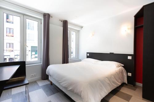 a bedroom with a white bed and two windows at Hotel Mimosa Paris in Paris