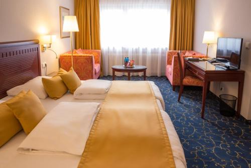 a hotel room with a large bed and a desk at Hotel Brunnenhof in Hanau am Main