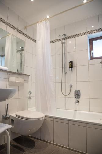 a white bathroom with a toilet and a shower at Hotel Brunnenhof in Hanau am Main