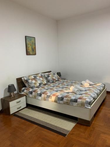 a bedroom with a bed with a plaid blanket and a night stand at Apartman Popovic Cetinje in Cetinje