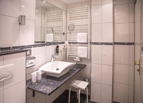 a white bathroom with a sink and a mirror at Hotel Brunnenhof in Hanau am Main