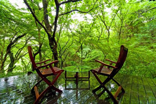 two chairs and a glass table on a deck at Sen-no-Mori in Aso