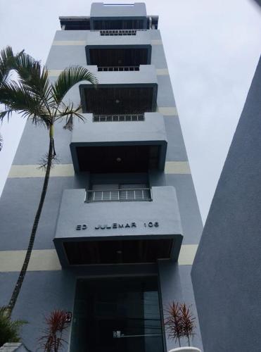 a tall building with a palm tree in front of it at Espaço Zen - Equilíbrio da Alma in Guarujá