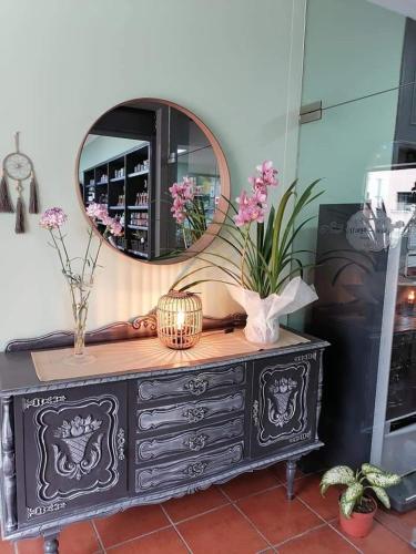 a mirror on top of a dresser with flowers on it at D'aqui e D'acolá - Pardieiros in Pardieiros