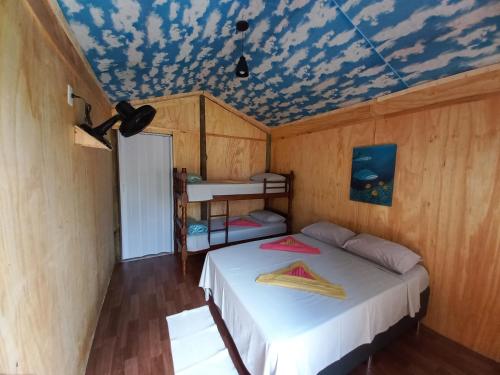 a bedroom with a bed and a ceiling with clouds at Piratas Cabanas Camping Bar in Paraty