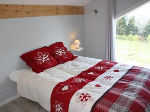Schlafzimmer mit einem Bett mit roten Kissen und einem Fenster in der Unterkunft Gîte Le Tholy, 4 pièces, 6 personnes - FR-1-589-217 in Le Tholy