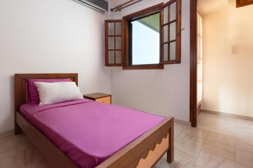 a bedroom with a bed with purple sheets and a window at Green Sunshine in Theologos