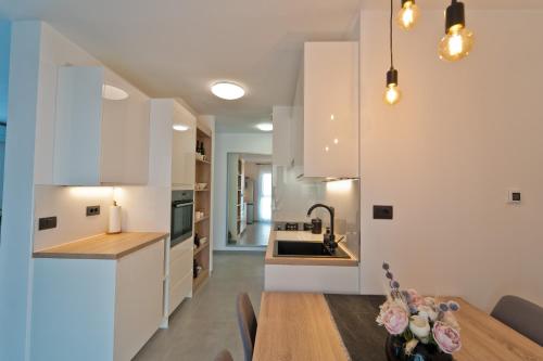 una cucina e una sala da pranzo con armadi bianchi e tavolo in legno di MaLeMi apartment a Pola (Pula)