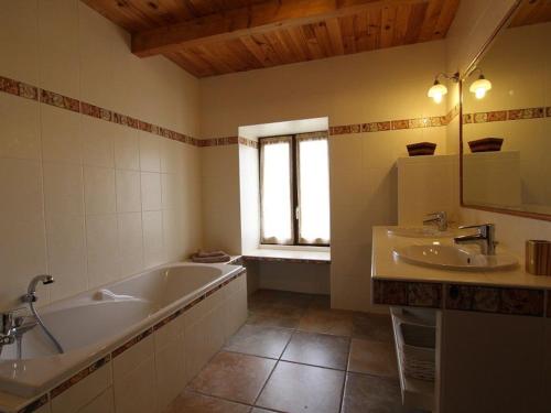 un bagno con vasca, 2 lavandini e finestra di Maison de charme en Margeride: terrasse, terrain clos, proche Saugues et chemin St-Jacques - FR-1-582-146 a Saugues