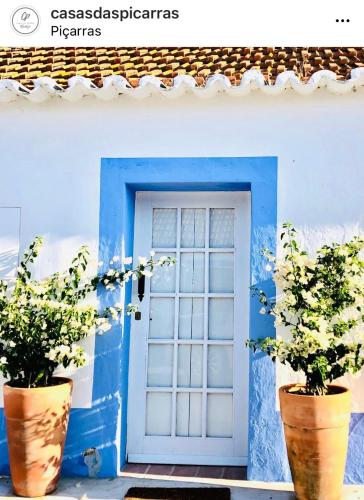 a blue door with two potted plants in front of it at Casas das Piçarras - Alentejo in Piçarra