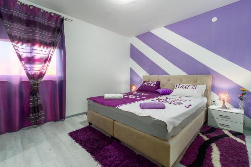 a purple and white bedroom with a bed and purple walls at Apartment Belma Poreč in Radmani