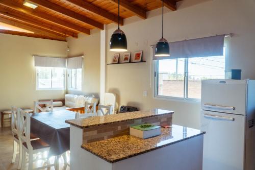 a kitchen with a table and a white refrigerator at Complejo Quiya - Casa El Algarrobo in Alta Gracia