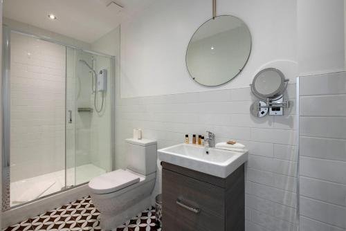 a bathroom with a toilet and a sink and a mirror at Trueman Court Luxury Serviced Apartments in Liverpool