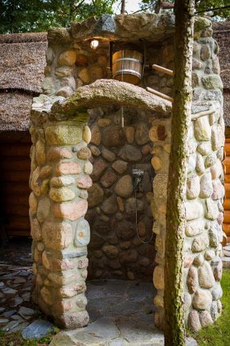 a stone building with a shower in a yard at SASKI ZAKĄTEK, WAKACJE W BAJKOWYM DOMKU!!! MAZURY, SAUNA, JEZiORO, POMOST, in Sasek Mały