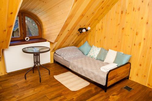 a couch in a room in a cabin with a table at SASKI ZAKĄTEK, WAKACJE W BAJKOWYM DOMKU!!! MAZURY, SAUNA, JEZiORO, POMOST, in Sasek Mały