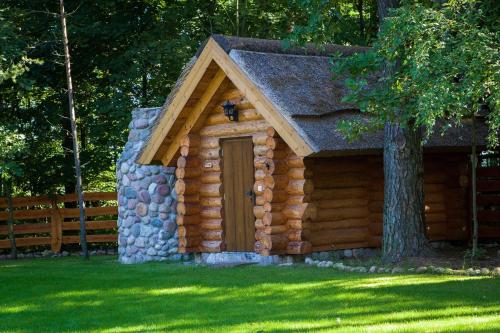 a log cabin with a door in the grass at SASKI ZAKĄTEK, WAKACJE W BAJKOWYM DOMKU!!! MAZURY, SAUNA, JEZiORO, POMOST, in Sasek Mały