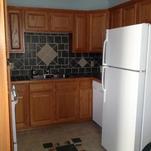 a kitchen with a white refrigerator and wooden cabinets at Boxwood Lodge Blowing Rock near Boone-University in Blowing Rock