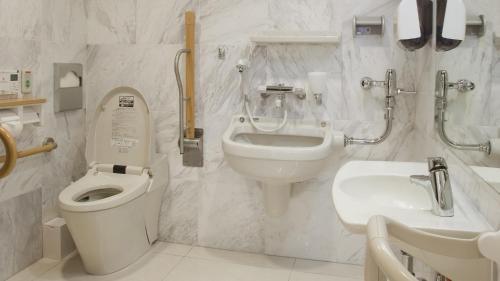 a white bathroom with a toilet and a sink at Toyoko Inn Yokohama-sen Fuchinobe-eki Minami-guchi in Sagamihara