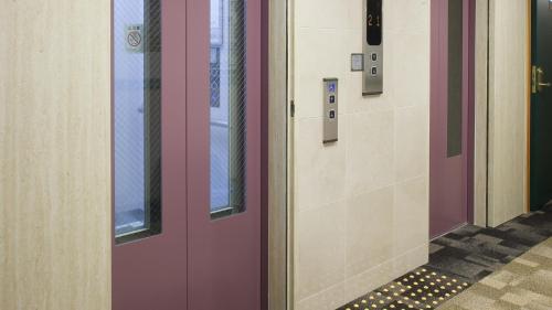 a row of doors in a hallway with a floor at Toyoko Inn Yokohama-sen Fuchinobe-eki Minami-guchi in Sagamihara