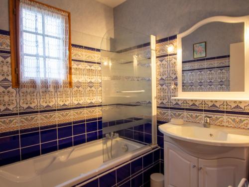 a blue tiled bathroom with a tub and a sink at Maison confortable près de Périgueux avec cheminée, jardin et animaux admis - FR-1-616-10 in Bassillac