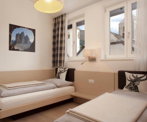2 Betten in einem Zimmer mit 2 Fenstern in der Unterkunft Residence Innichen - San Candido in Innichen