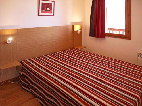 a large striped bed in a room with a window at Appartement Les Orres, 2 pièces, 4 personnes - FR-1-322-425 in Les Orres